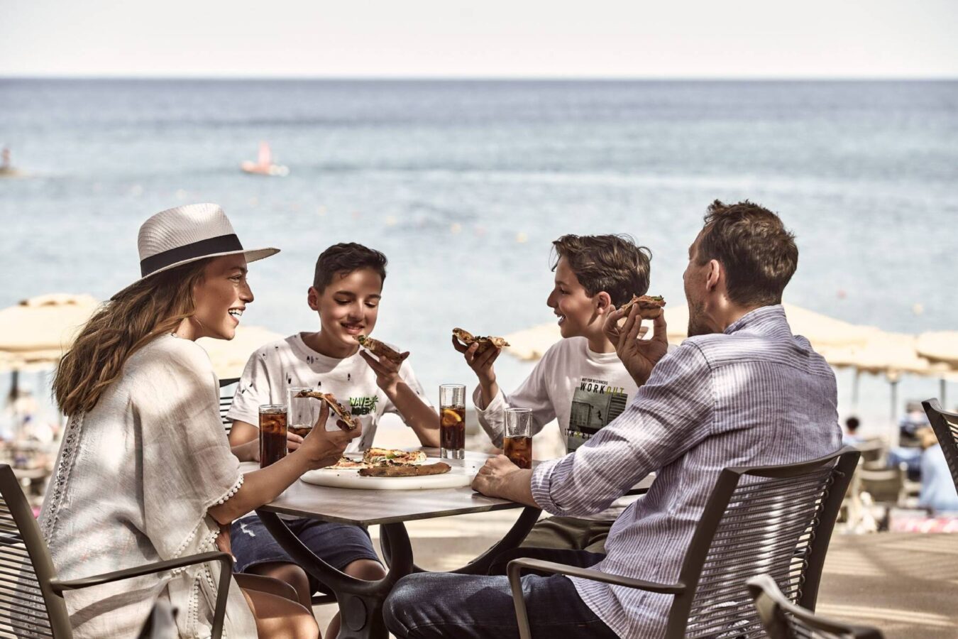 Parents and two children enjoying lunch of the beach during their family holiday in Rhodes with H Hotels Collection.